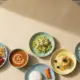 Verschiedene Mittagessen nebeneinander auf einem Kita-Tisch bei Allergie in der Kita