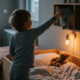 Kind greift abends nach einem Buch am Bett, Teddybaer liegt bereit