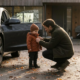 Vater zieht Baby im Herbst für den Weg zum Auto die Jacke an
