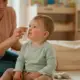 Grippeimpfung bei Krippenkindern: was sie leistet und was nicht - Kind wird von einer Betreuungsperson die Nase geputzt